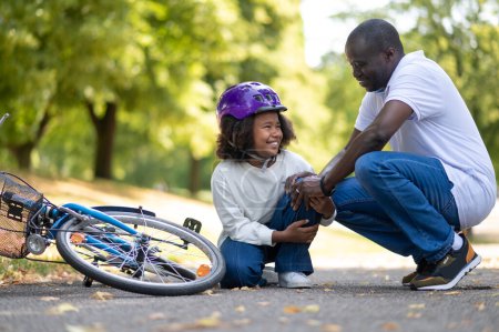Photo for Accident. Father helping his kid after falling from the bike - Royalty Free Image
