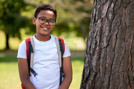 Photo for Happy boy. Dark-skinned boy in eyeglasses looking contented and happy - Royalty Free Image