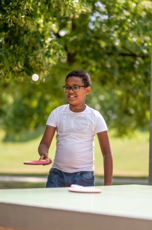 Téléchargez les photos : Tennis de table. Un garçon en t-shirt blanc jouant au tennis de table - en image libre de droit