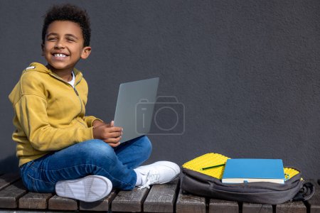 Photo for School time. Curly-haired schoolboy with laptop doing lessons - Royalty Free Image