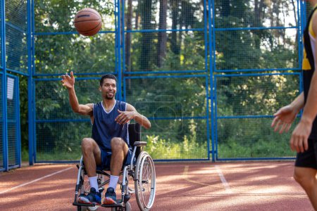 Photo for Active basketball players playing the match while black guy using wheelchairs on sports court. - Royalty Free Image