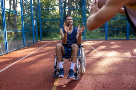 Photo for Black athlete with disabilities and his friend playing basketball outdoors on court. - Royalty Free Image