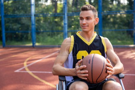 Foto de Caucásico jugador de baloncesto hombre en silla de ruedas tiene discapacidad jugando en la cancha, sosteniendo la pelota. - Imagen libre de derechos