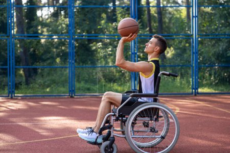 Foto de Hombre caucásico con discapacidad en silla de ruedas en un parque, tiene entrenamiento y diversión de fin de semana o partido de baloncesto activo. - Imagen libre de derechos