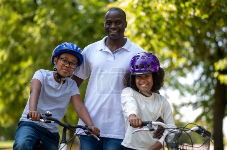 Photo for Family weekend. African american family having good time in a park and riding bikes - Royalty Free Image