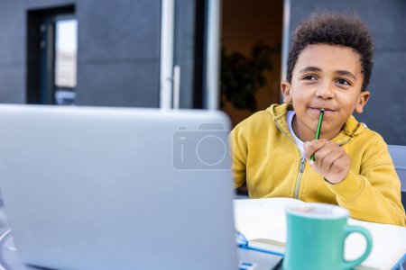 Photo for Doing lessons. African american schoolboy doing lessons and looking involved - Royalty Free Image