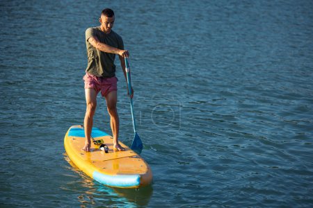 Photo for Athletic man on sub board floating on ocean sea. - Royalty Free Image