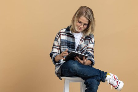 Téléchargez les photos : Adolescent avec gadget. Blonde adolescent avec un dispositif moderne à la recherche satisfait - en image libre de droit