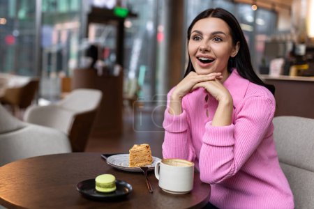 Téléchargez les photos : Au café. Une fille dans une chemise rose assise dans un café et se sentant positive - en image libre de droit