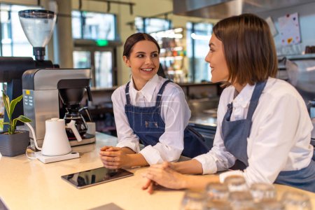 Photo for Coffee shop. Smiling girls in apron standing in the coffee shop - Royalty Free Image