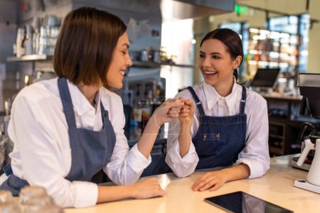 Photo for Coffee shop. Smiling girls in apron standing in the coffee shop - Royalty Free Image