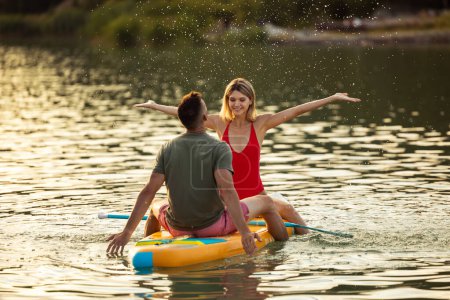 Téléchargez les photos : Heureux surfeurs homme et femme au coucher du soleil reposant sur l'eau. - en image libre de droit