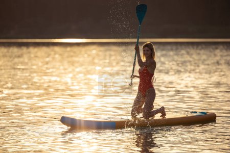 Téléchargez les photos : Belle fille flottant sur le supboard sur une rivière ou un lac. - en image libre de droit