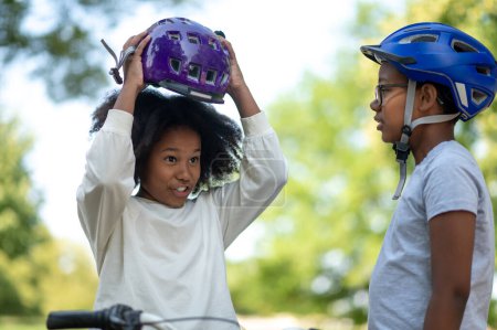 Photo for Before the ride. Siblings helping each other to put on a protective hemlet - Royalty Free Image