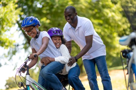 Foto de Cabalga en el parque. Lindos niños afroamericanos montando bicicletas en el parque - Imagen libre de derechos
