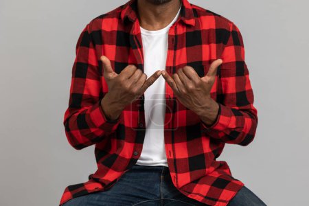 Photo for Unrecognizable black bearded man wearing red checkered shirt showing deaf-mute gestures posing isolated over gray studio background. - Royalty Free Image
