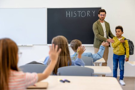 Photo for New comer. Teacher introducing a new boy to the classmates - Royalty Free Image