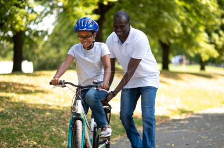 Photo for Ride in a park. Happy dad teaching his kids to ride a bike - Royalty Free Image