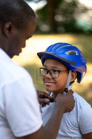 Foto de Cycler.Dad fijar un dobladillo protector en la cabeza de sus hijos - Imagen libre de derechos