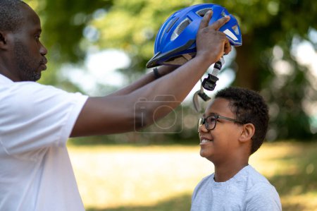 Téléchargez les photos : Cycle.Dad fixer un ourlet protecteur sur la tête de ses enfants - en image libre de droit