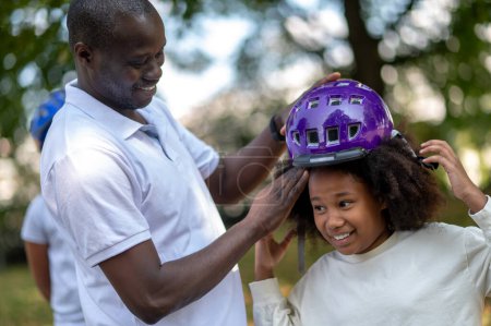 Téléchargez les photos : Cycle.Dad fixer un ourlet protecteur sur la tête de ses enfants - en image libre de droit