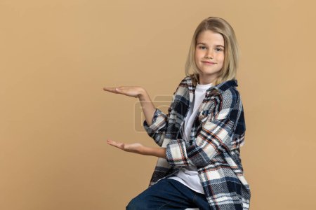 Foto de Una chica en un estudio. Linda chica adolescente rubia con camisa a cuadros sentada en la silla en un estudio - Imagen libre de derechos