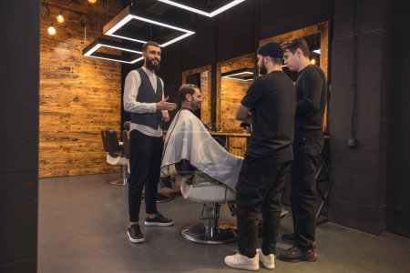 Téléchargez les photos : Coiffeur professionnel enseigne aux étudiants à faire des coiffures pour hommes sur le modèle. - en image libre de droit