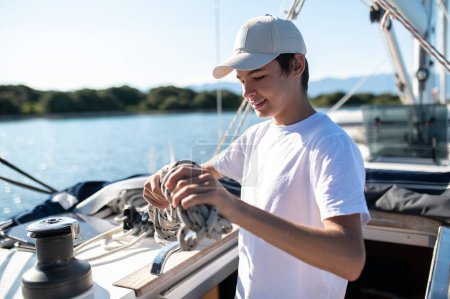 Téléchargez les photos : Loisirs. Adolescent en t-shirt blanc sur yacht regardant satisfait - en image libre de droit