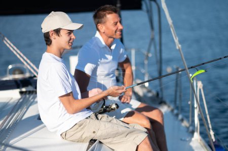 Téléchargez les photos : Pêche. Papa et fils passent du temps ensemble sur le yacht et fisihing - en image libre de droit