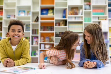 Photo for Children sitting in school library having fun while break waiting for lesson. - Royalty Free Image