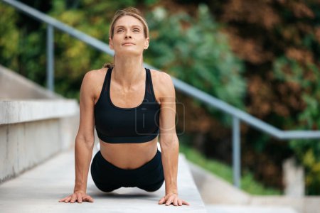 Photo for Relaxation practice. Fitness training. Fresh energy. Attractive woman doing yoga exercises outdoor, stretching body. - Royalty Free Image