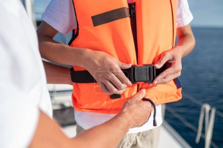 Téléchargez les photos : Sécurité pendant le yachting. Gros plan d'une personne portant un gilet de sauvetage - en image libre de droit