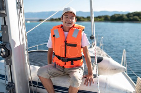 Téléchargez les photos : Sur le bateau. Garçon souriant en gilet de sauvetage sur le bateau - en image libre de droit