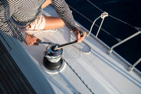Téléchargez les photos : Yacht. Photo rapprochée des mains de mans fixant la corde sur un yacht - en image libre de droit