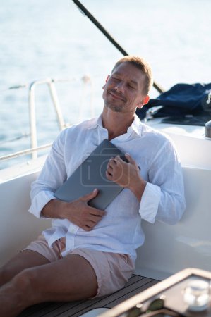 Photo for Digital nomad.Successful mature man with a laptop working on a yacht - Royalty Free Image