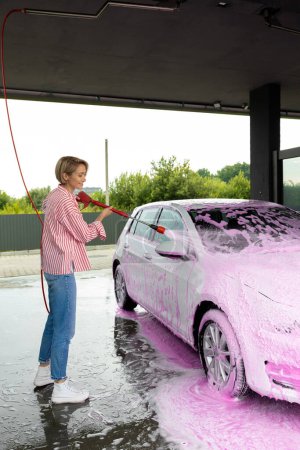 Photo for Car wash. Woman cleaning a white car the car wash - Royalty Free Image