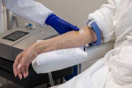 Photo for Unrecognizable woman receiving vitamin IV infusion drip in wellness center or beauty salon. - Royalty Free Image