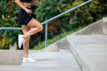 Photo for Burn fat. Attractive sportswoman. Leg strength. Joggers park run. Athletic unrecognizable woman doing cardio training on stairs. - Royalty Free Image