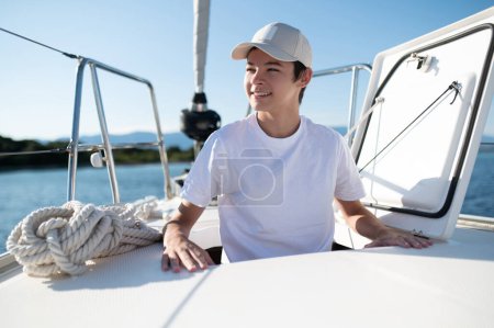 Téléchargez les photos : Garçon sur le yacht. Souriant adolescent sur un yacht à l'air satisfait - en image libre de droit