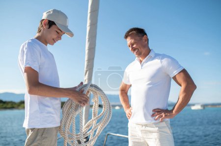 Photo for Sunny day on a yacht. Father and son sailing on the yacht on a sunny day - Royalty Free Image