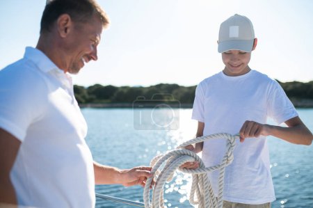 Téléchargez les photos : Journée ensoleillée sur un yacht. Père et fils naviguant sur le yacht par une journée ensoleillée - en image libre de droit
