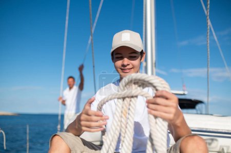 Téléchargez les photos : Journée ensoleillée. Homme mûr et son fils sur le yacht par une belle journée ensoleillée - en image libre de droit