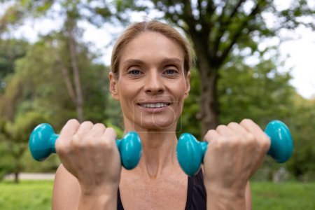 Photo for Outdoor exercise. Fit and healthy. Sporty lifestyle. Athletic woman training hands with dumbbells has workout in park. - Royalty Free Image