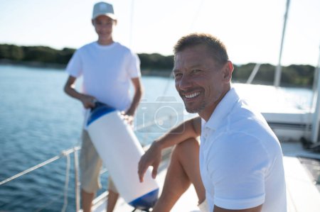 Téléchargez les photos : Loisirs. Fils et papa yachting et regarder heureux et satisfait - en image libre de droit