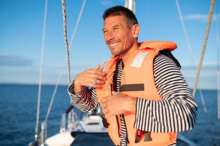 Téléchargez les photos : Voyage. Homme sur un yacht portant un gilet de sauvetage - en image libre de droit