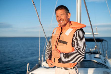 Photo for Journey. Man on a yacht putting on a life jacket - Royalty Free Image