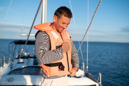 Téléchargez les photos : Voyage. Homme sur un yacht portant un gilet de sauvetage - en image libre de droit