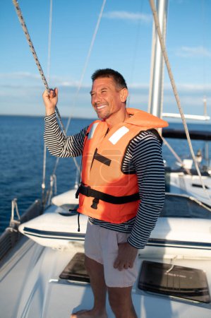 Téléchargez les photos : Sur un yacht. Mature homme dans un gilet de sauvetage sur un yach se sentir bien - en image libre de droit
