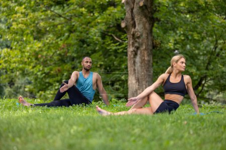 Foto de Balance de yoga. Estilo de vida adecuado. Ejercicio saludable. Hombre y mujer haciendo ejercicios de yoga en el parque verde. - Imagen libre de derechos