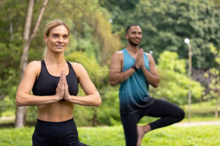 Téléchargez les photos : La santé pose. Équilibre de yoga. Exercice sain. Homme et femme faisant des exercices de yoga dans un parc vert. - en image libre de droit